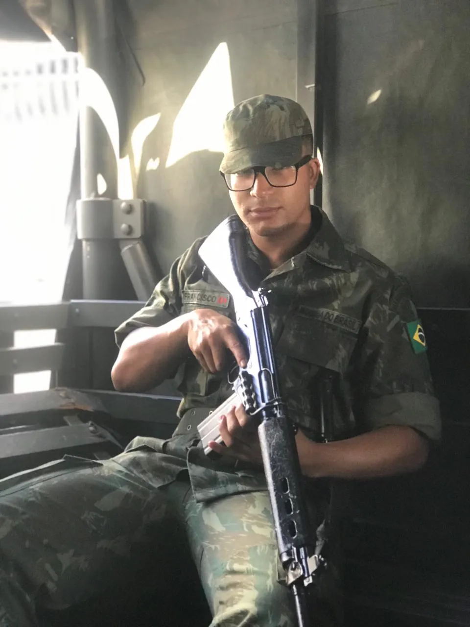 Daniel P Francisco in camouflage uniform and cap, seated inside a vehicle during a field mission
