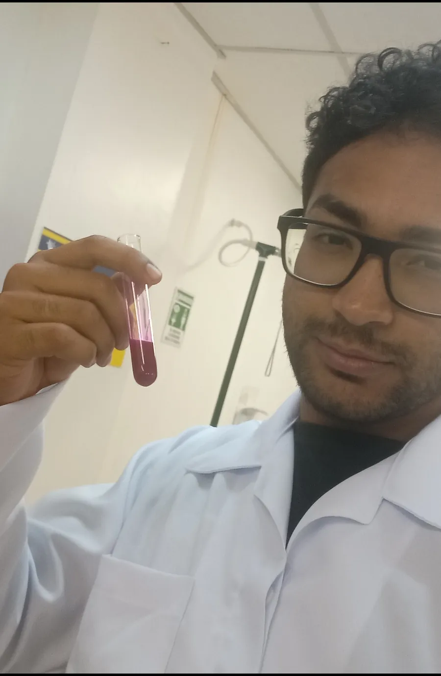 Daniel P Francisco de jaleco segurando um tubo de ensaio com solução roxa
