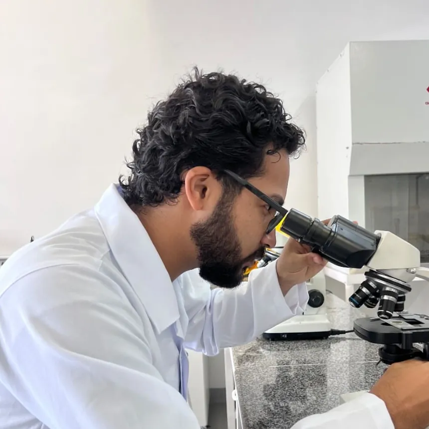 Daniel P Francisco de jaleco, observando ao microscópio em um laboratório
